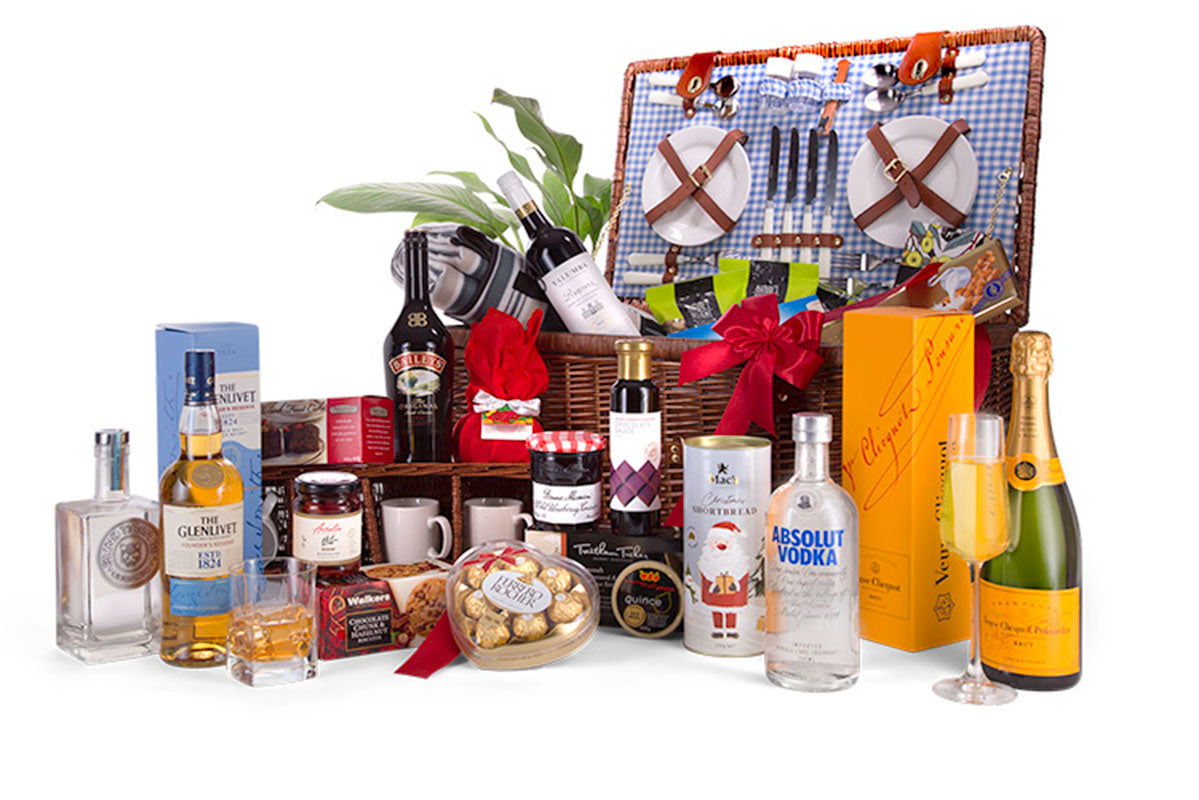 wicker picnic basket with picnic set in lid and hamper contents displayed in front
