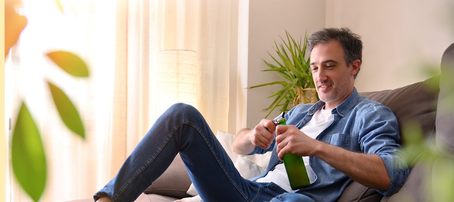 a man on a sofa opening a bottle of beer