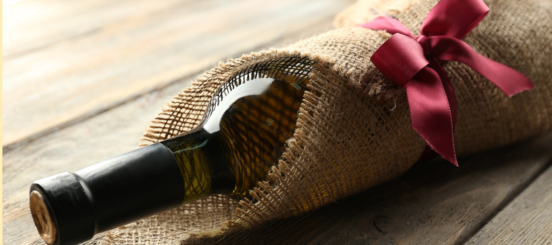 bottle of wine wrapped in a hessian cloth tied with a red ribbon and bow