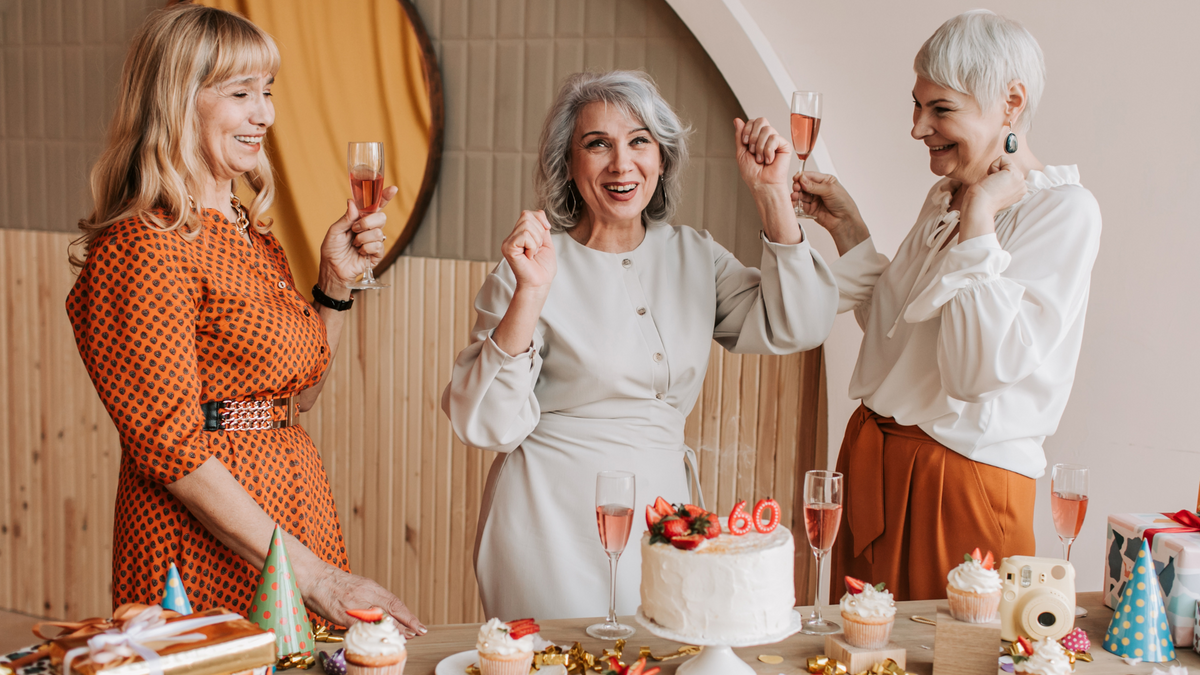 Women enjoying a glass of sparkling rosé, next to a table with a 60th birthday cake