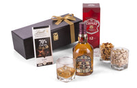 Open bottle of Chivas Regal blended Scotch whisky with a glass on a wooden surface, showcasing the rich amber color.