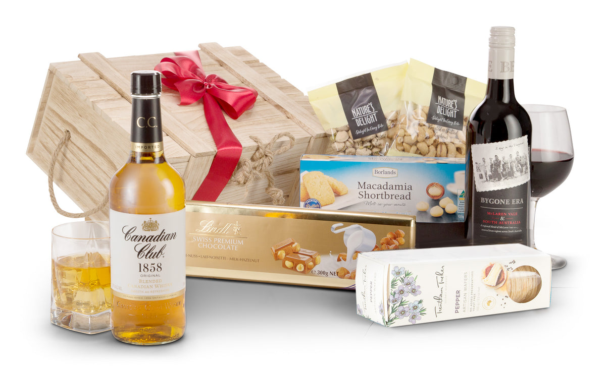 Open bottle of Interhampers Whisky and Red wine with glasses and garnishes on a wooden table.